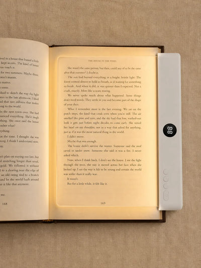 Top view of Lumalli lying flat over and illuminating a book page